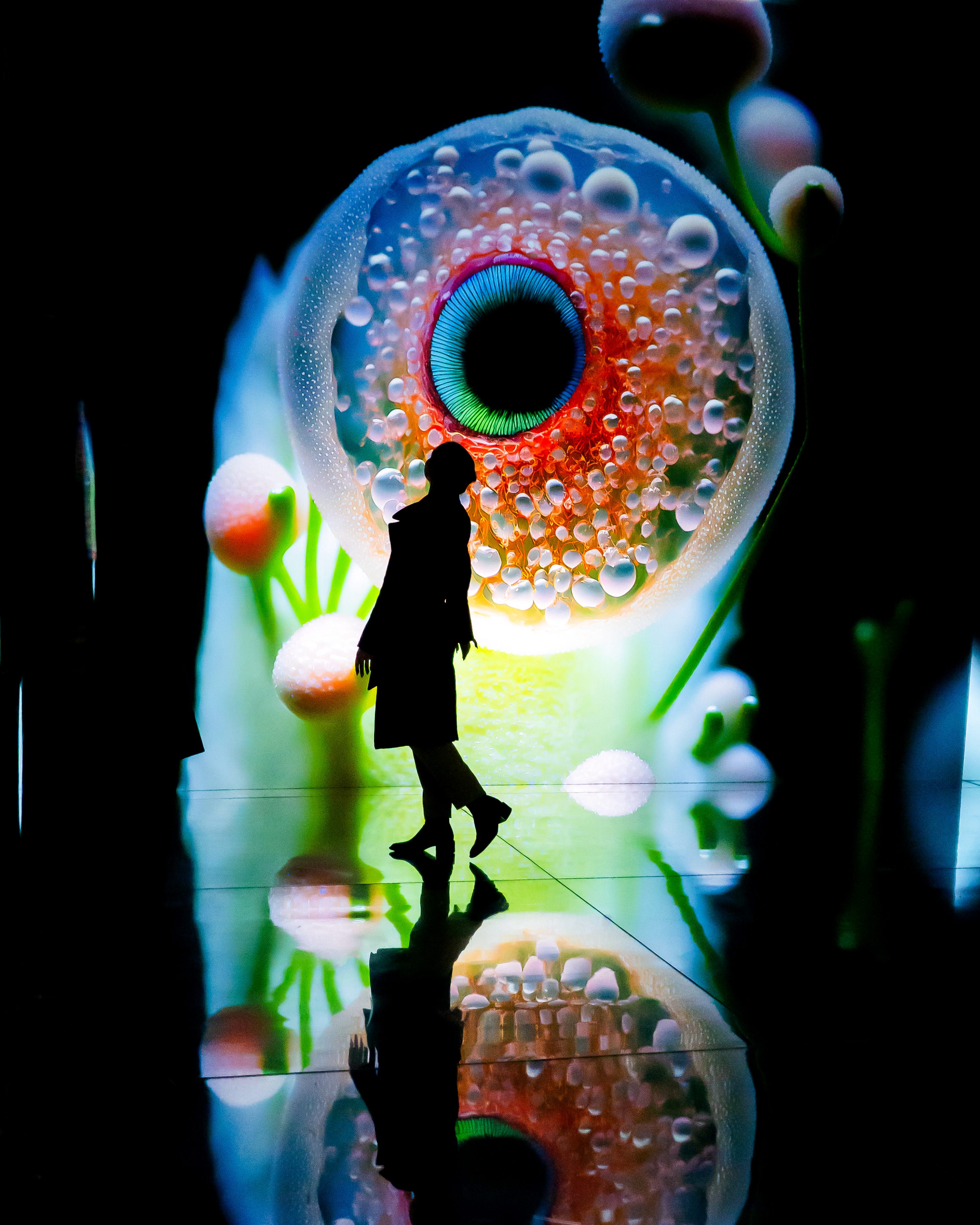 Silhouette walking past giant cellular eye projection