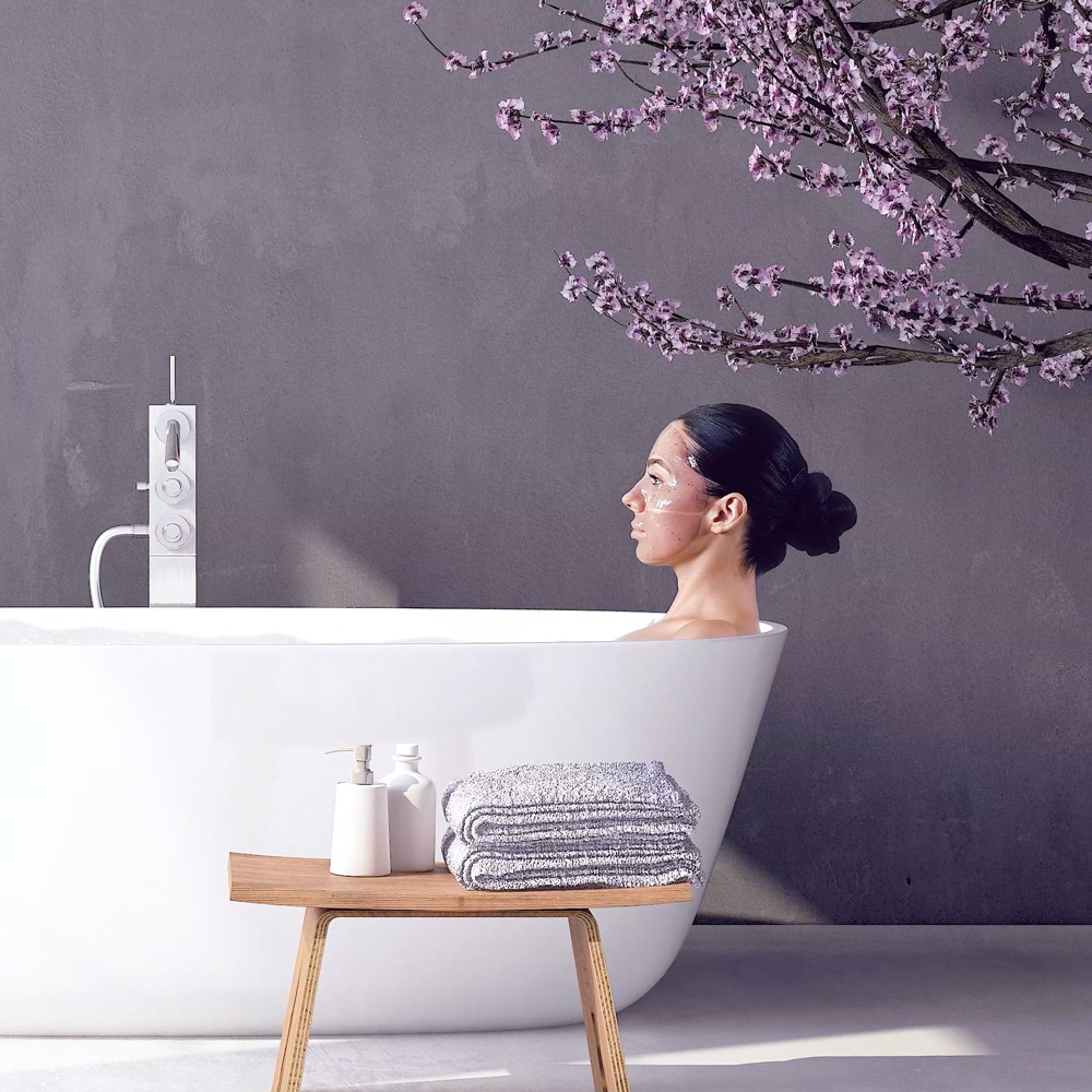 Woman relaxing in white bathtub with face mask and cherry blossoms